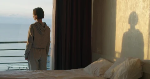 Person seated calmly by a window taking a slow, relaxed breath